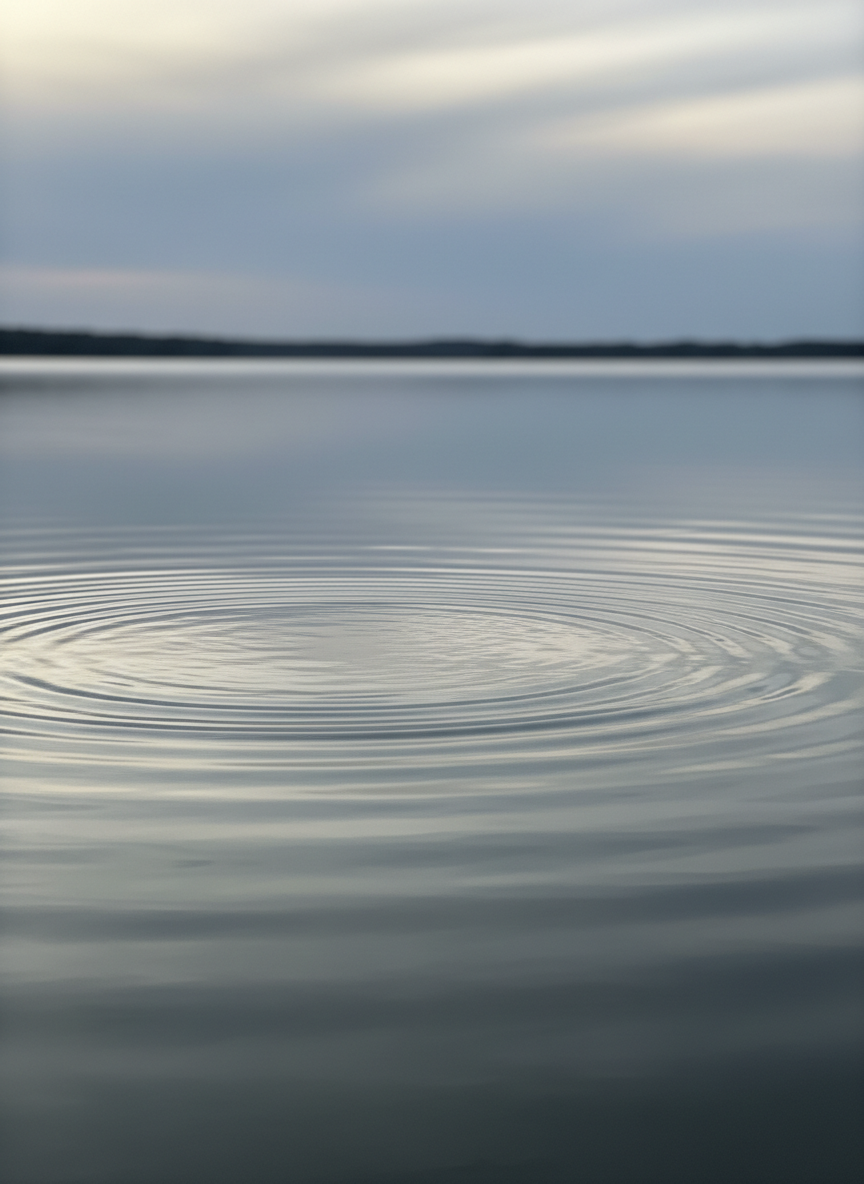 An understated close-up photograph of gentle water ripples on a lake surface at overcast dusk, soft reflections of a grey sky, muted sage and misty blue-grey tones.